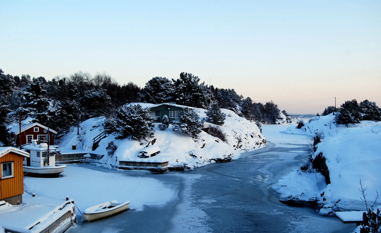 Kjønnøya i desember: islagt sund, furu, svaberg og naust ved Trosbyfjorden.